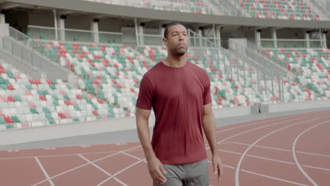 Porträt-Eines-Afroamerikanischen-Schwarzen-Mannes,-Der-Sich-Vor-Dem-Laufen-Am-Frühen-Morgen-Auf-Einer-Leeren-Stadionstrecke-Aufwärmt.-Aufgenommen-Mit-Anamorphotischem-Objektiv